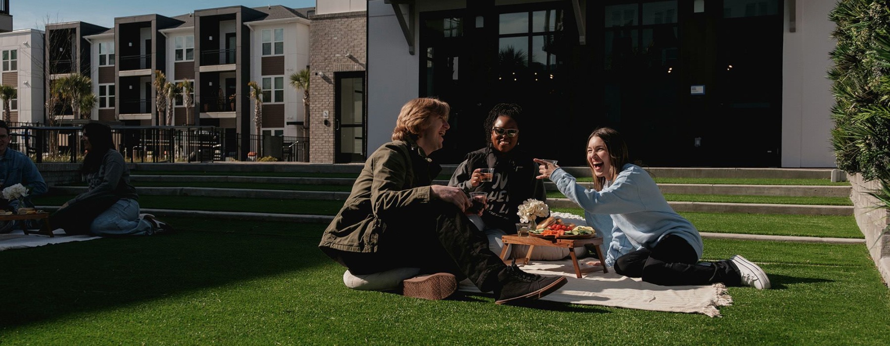 A group of people sitting on the grass having a picnic.